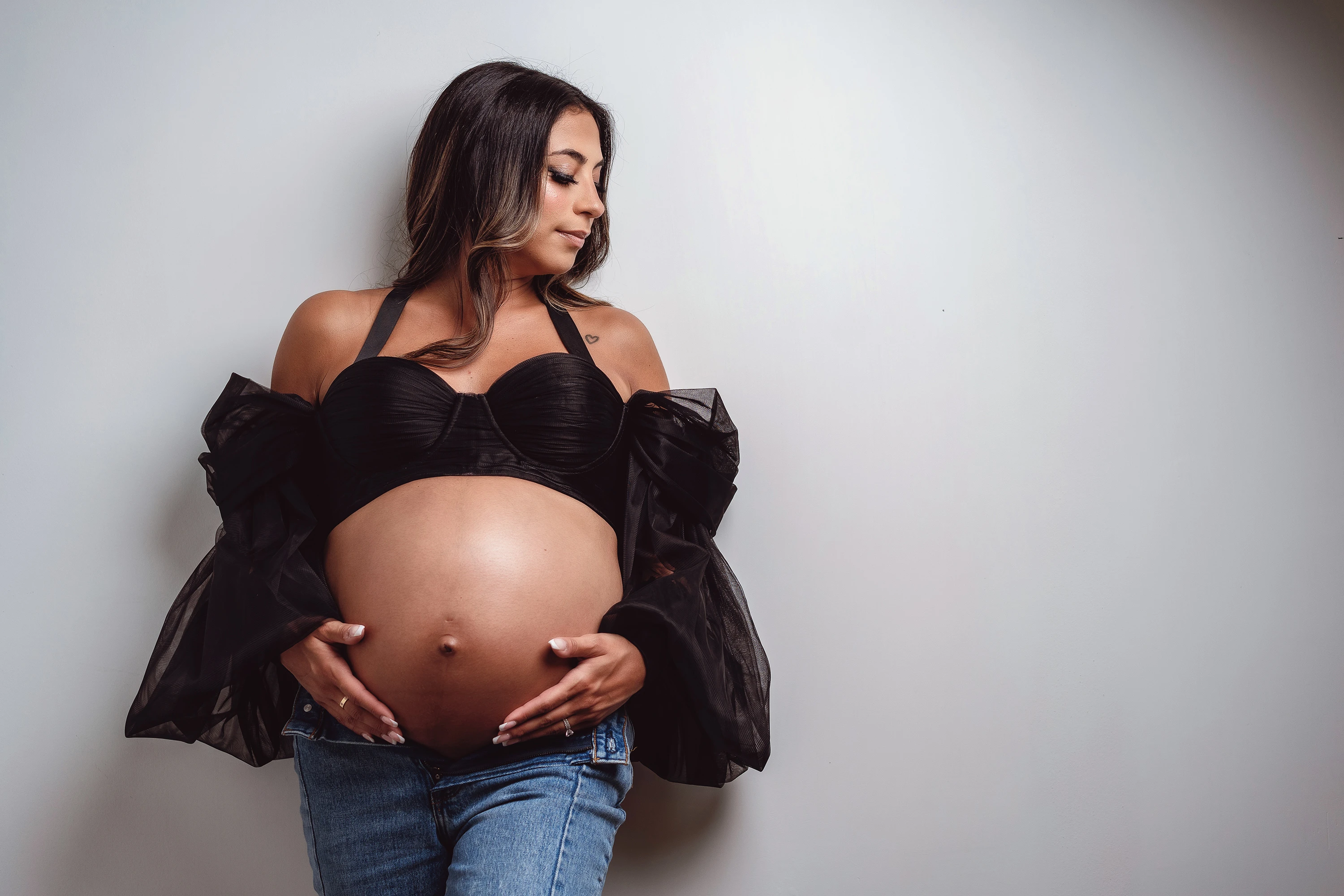 maternity photo of woman wearing black halter top holding her stomach