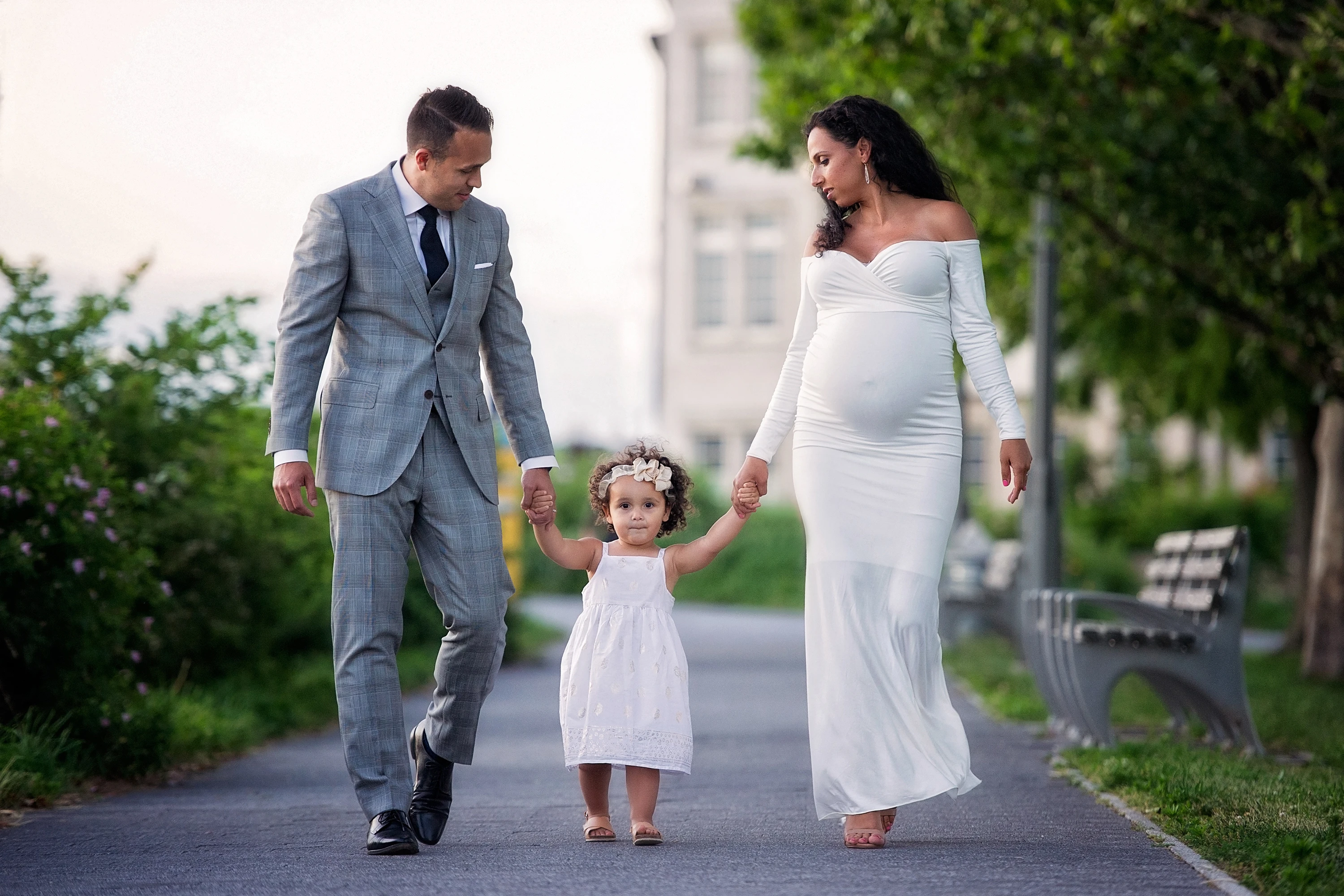 husband walking with his pregnant wife and holdings hands of little girl walking outside