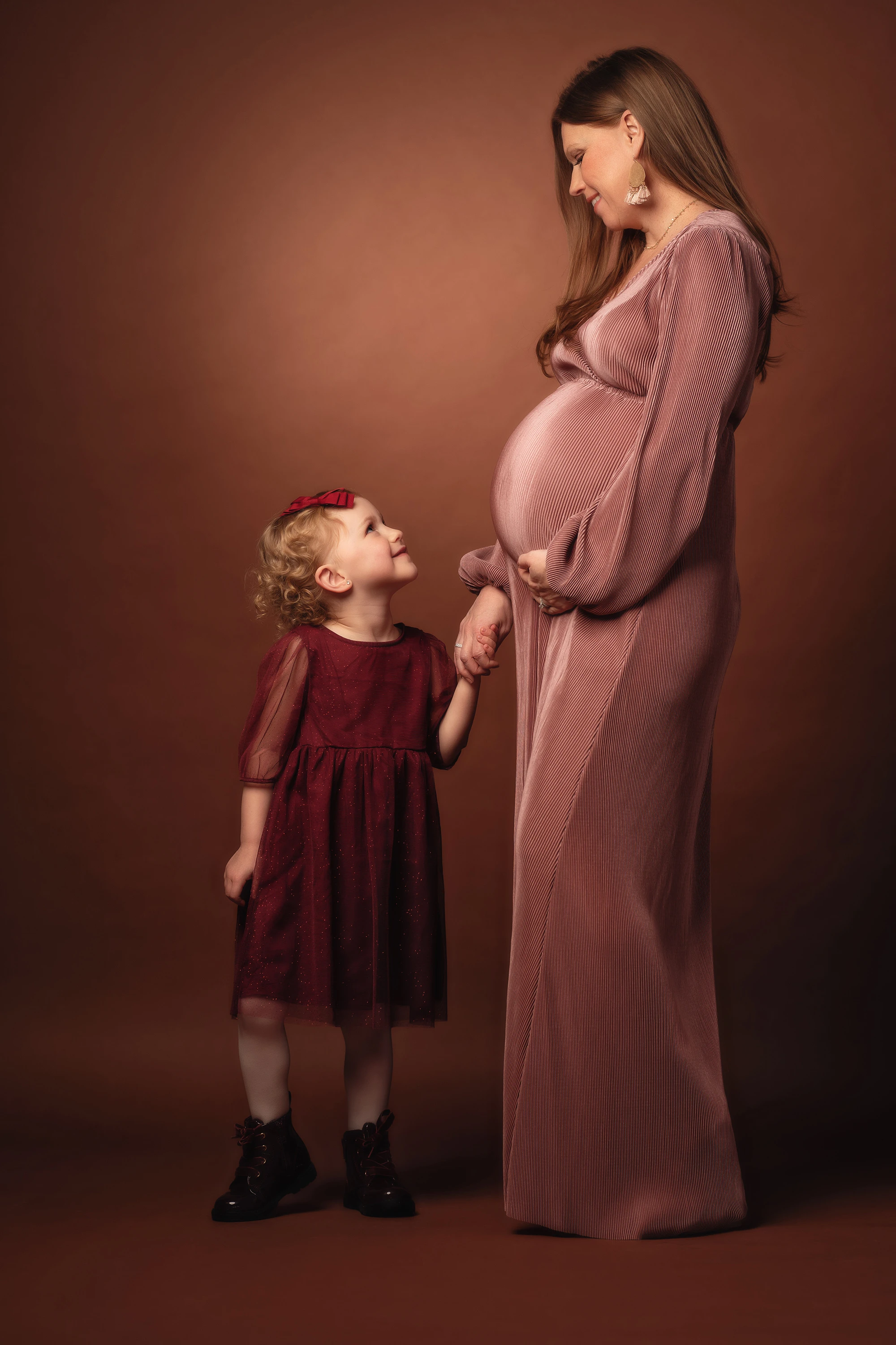 maternity photo of little girl holding her pregnant mother's hand