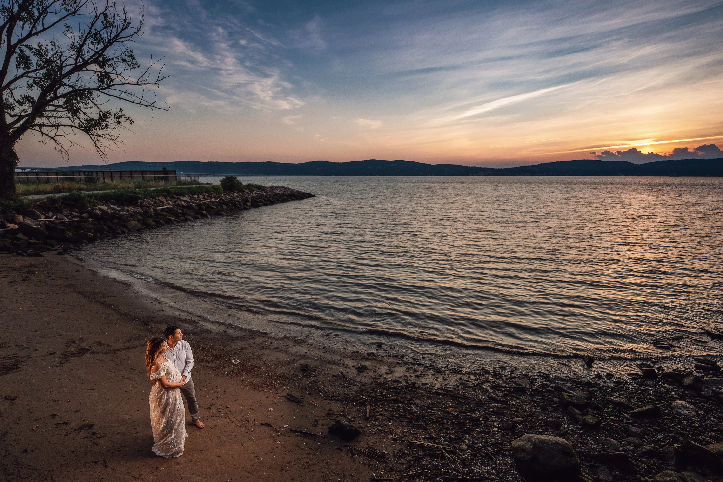 maternity photo of man and woman at sunset looking out to the horizon