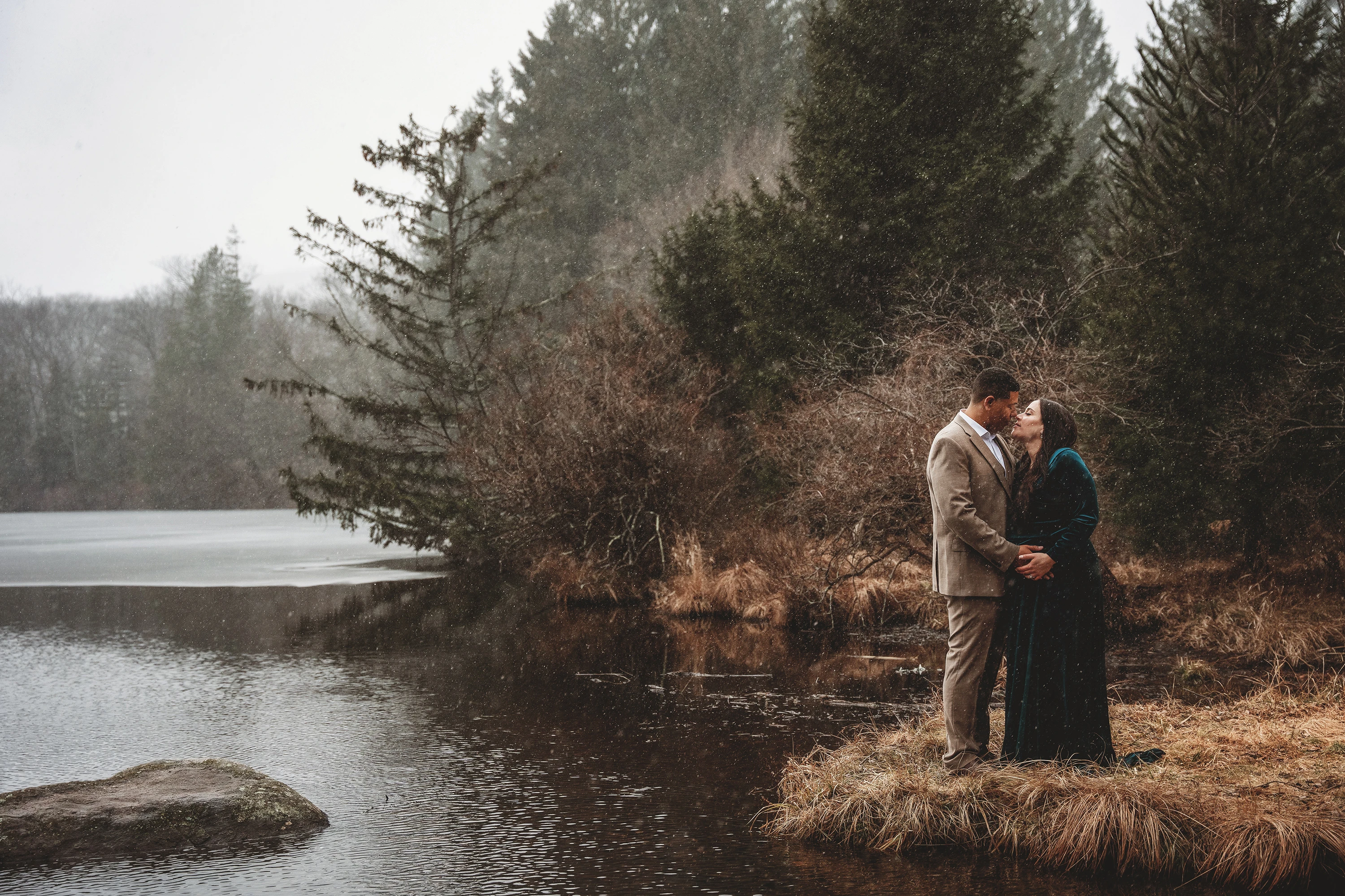 maternity photo of man and woman kissing outside
