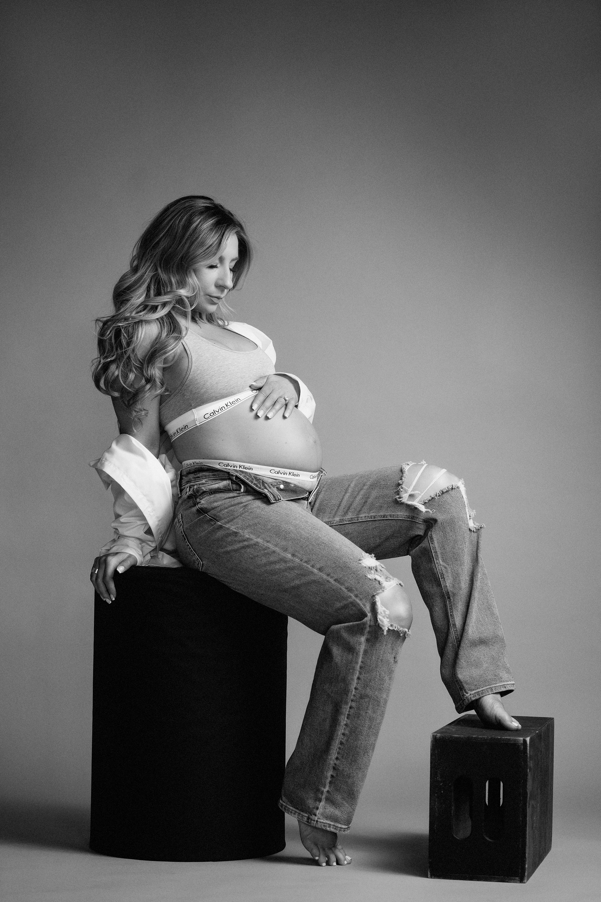 maternity photo of woman in black and white wearing jeans and sports bra
