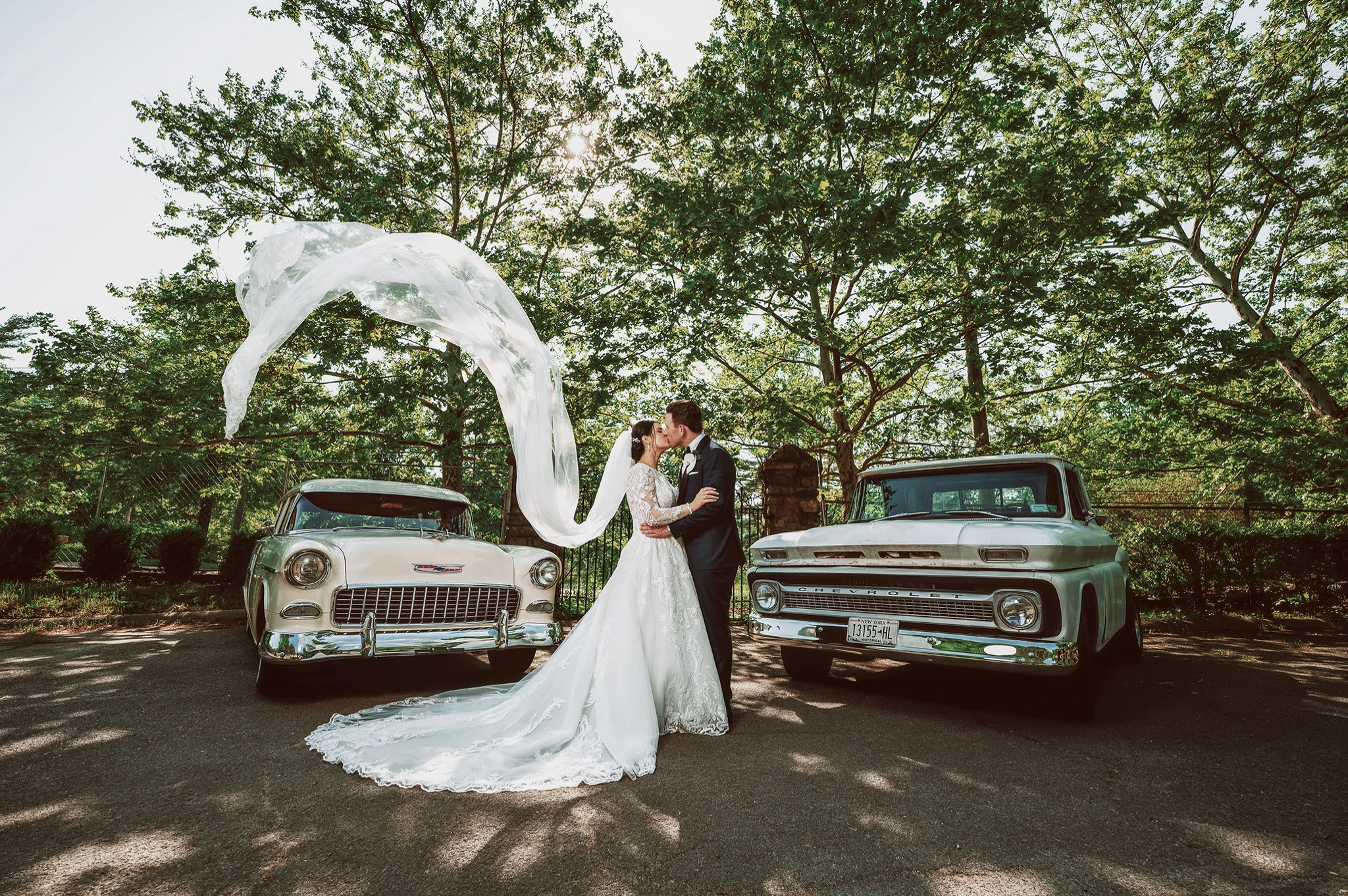 Photo of bride and groom at Old Tappan Manor standing in front of classic cars