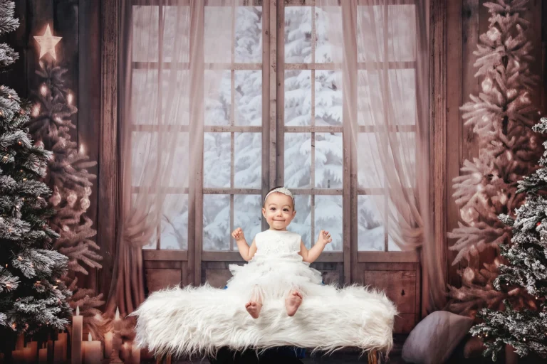 Baby in white dress on white bench for christmas photoshoot