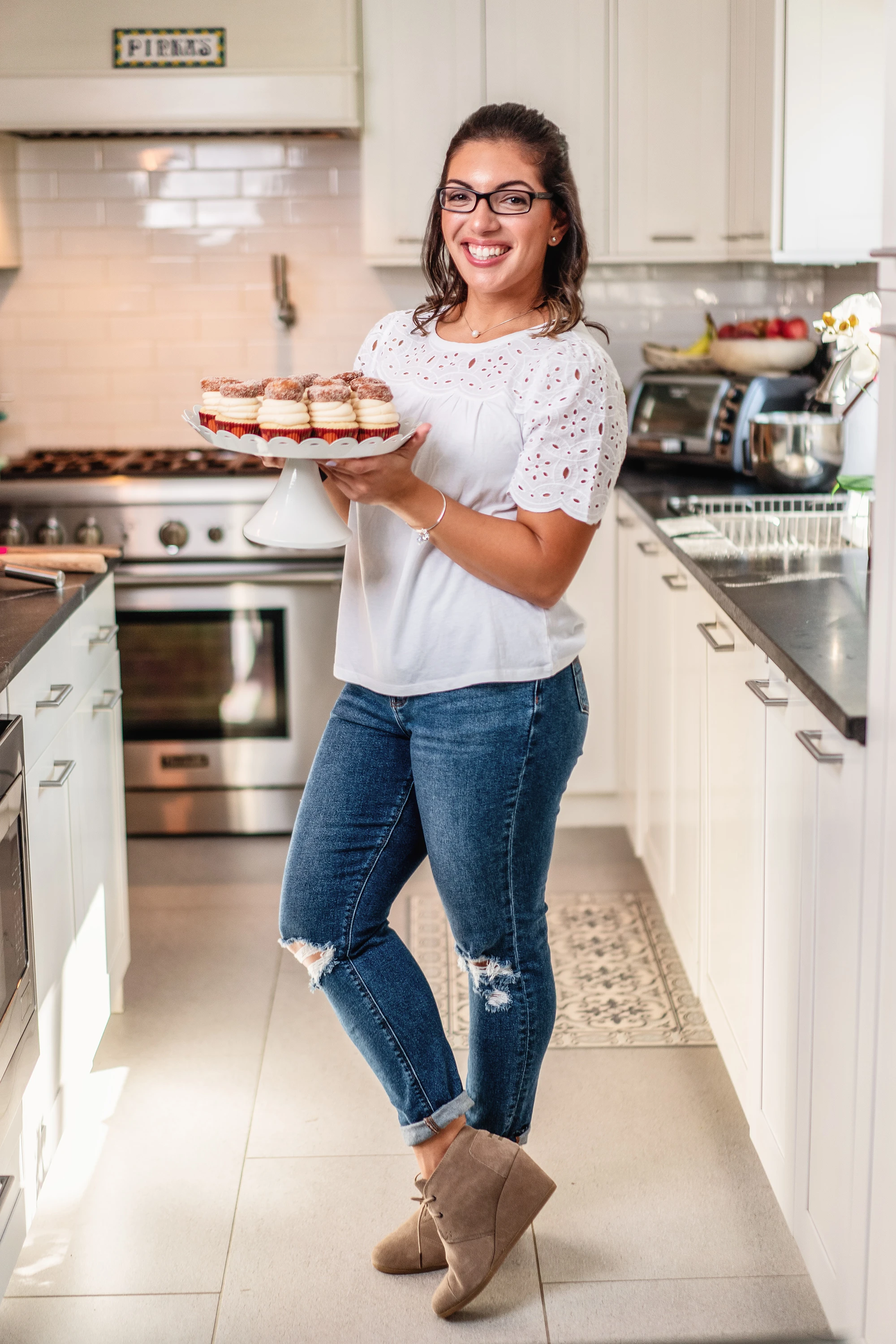 creative portrait of woman posing with freshly baked cupcakes in kitchen