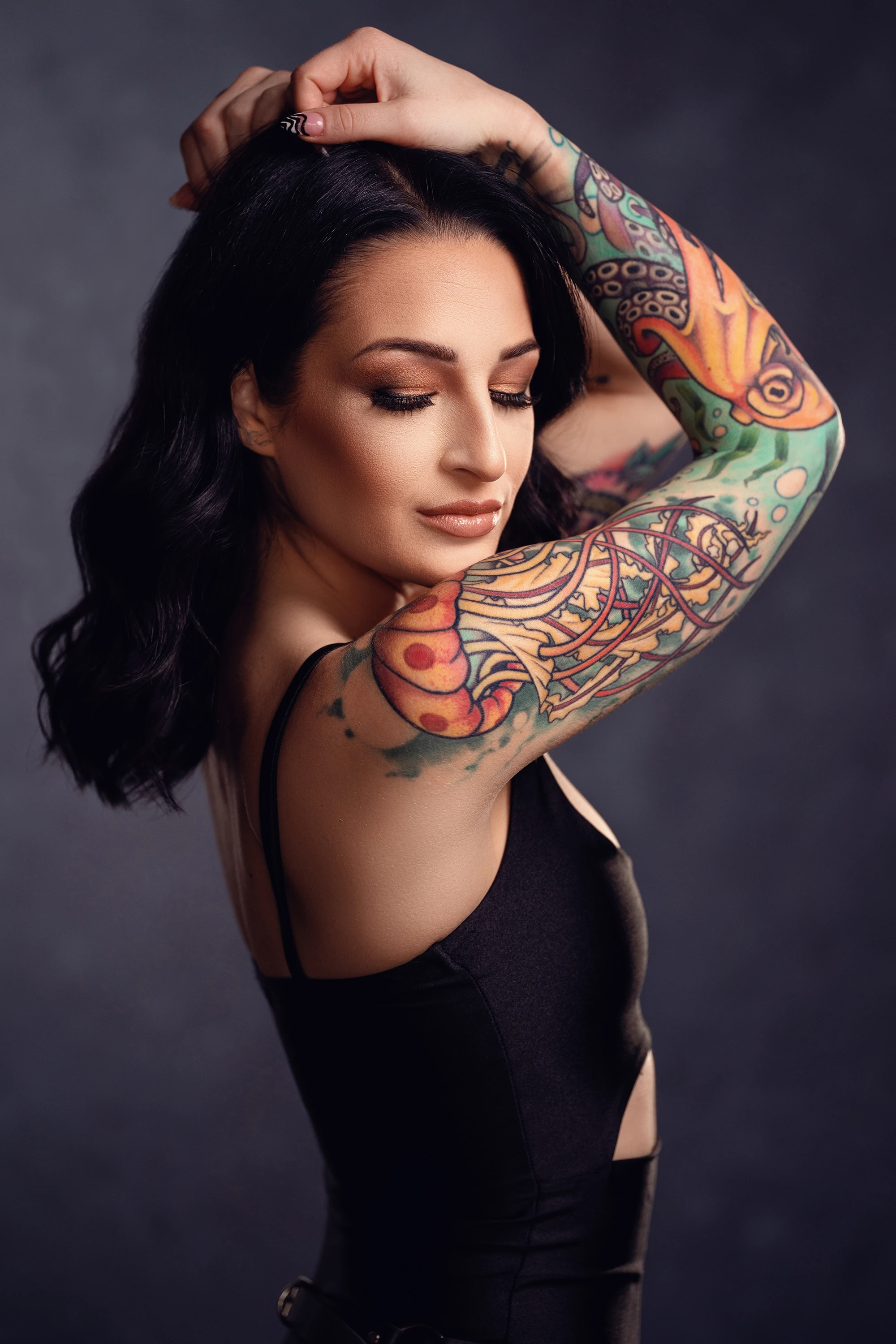 portrait of woman in black shirt and colorful tattoos on her arm