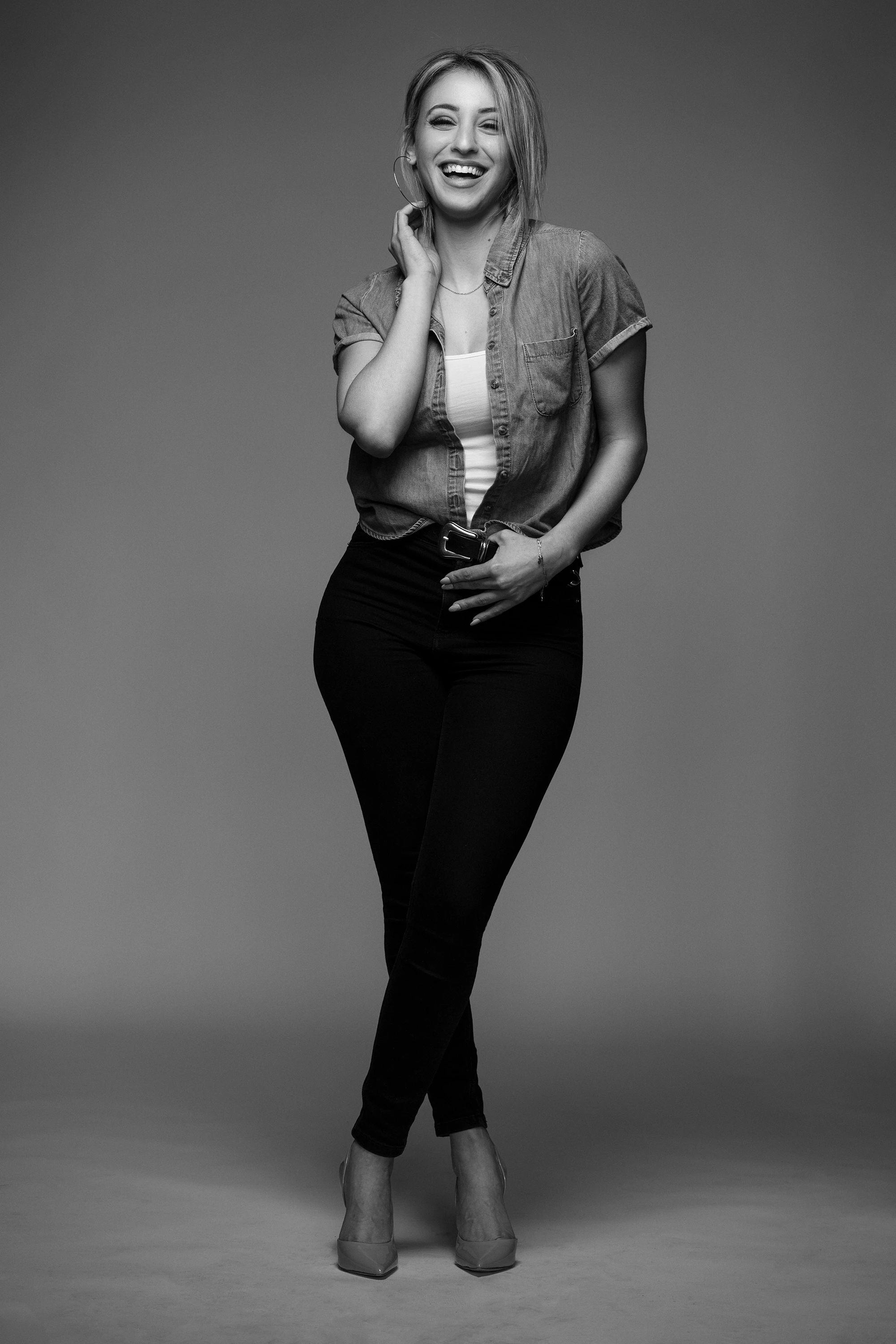 full body portrait of woman in black and white wearing jeans, boots and a button down shirt