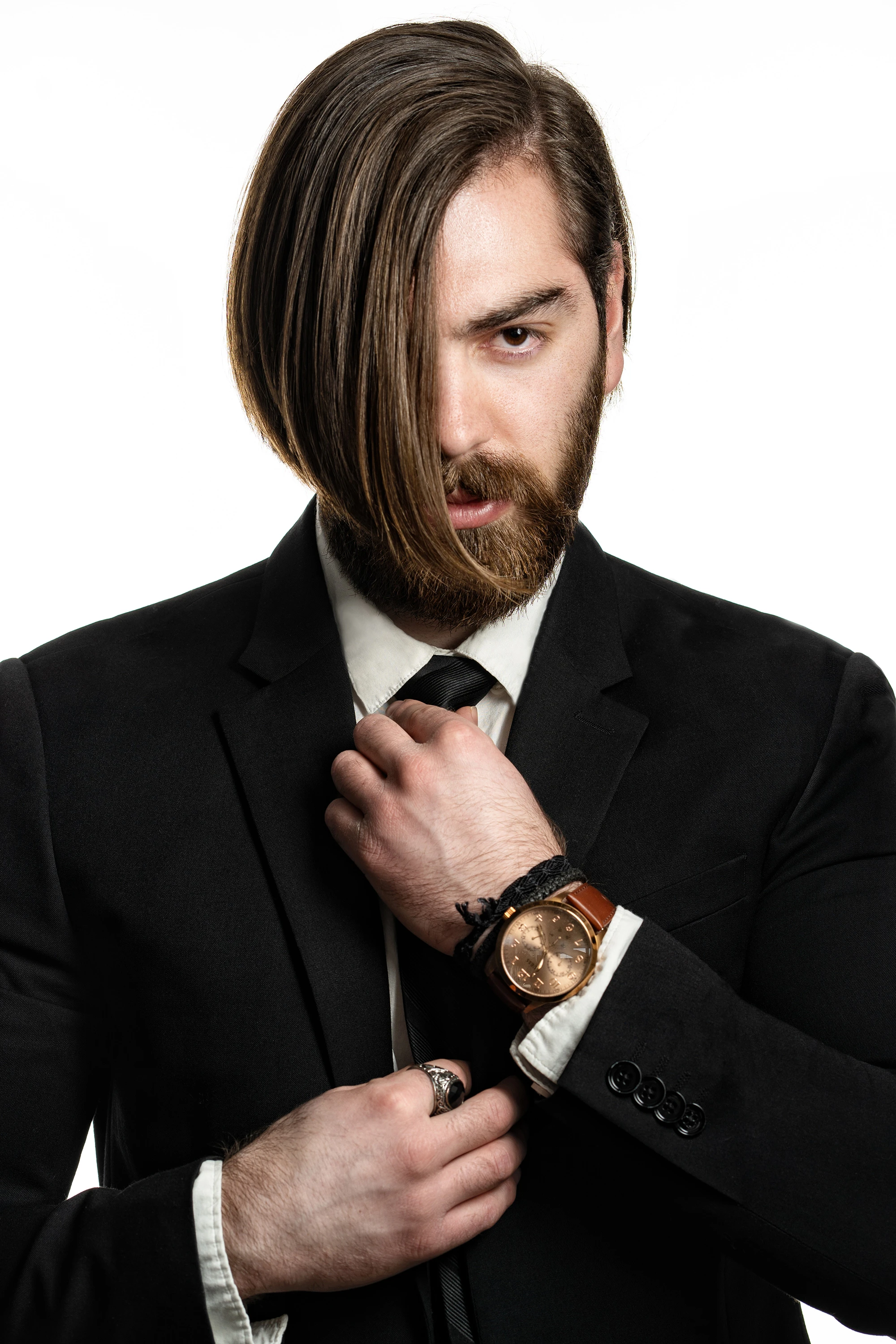Creative portrait of man in black suit wearing a luxury watch and ring