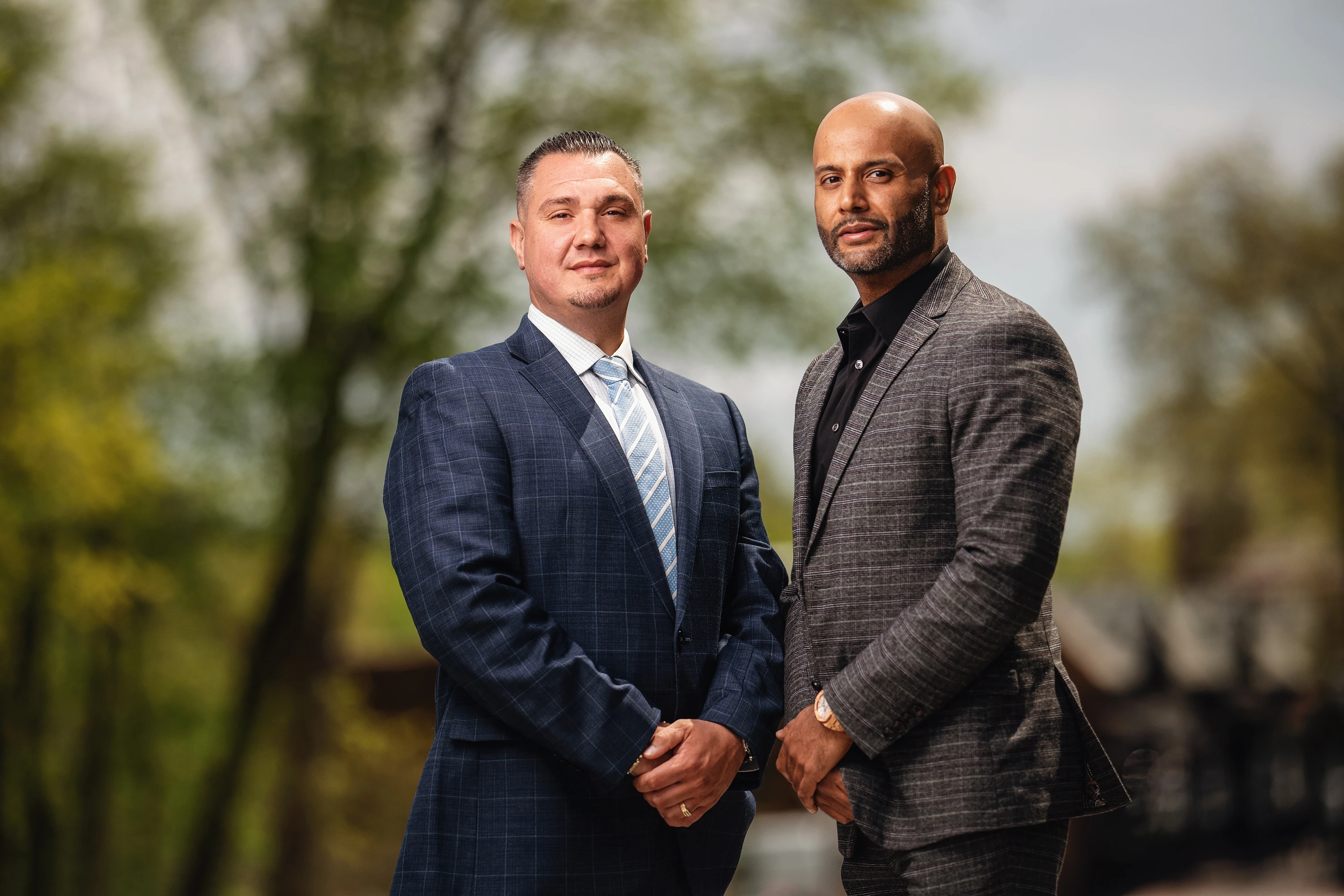 Professional headshots of two business partners, one wearing a blue suit, the other a plaid blazer