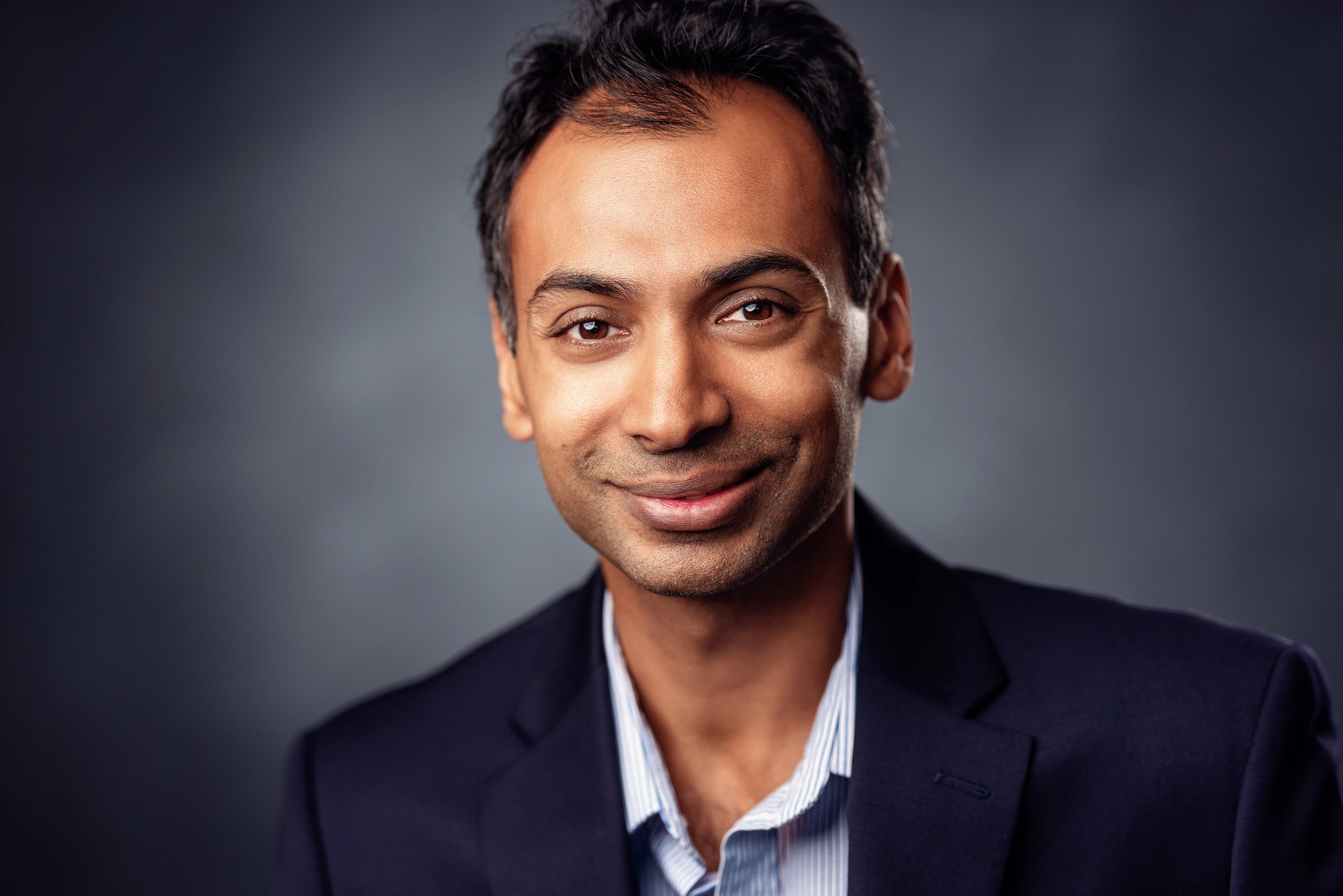 close up headshot of man in button down shirt and blue blazer
