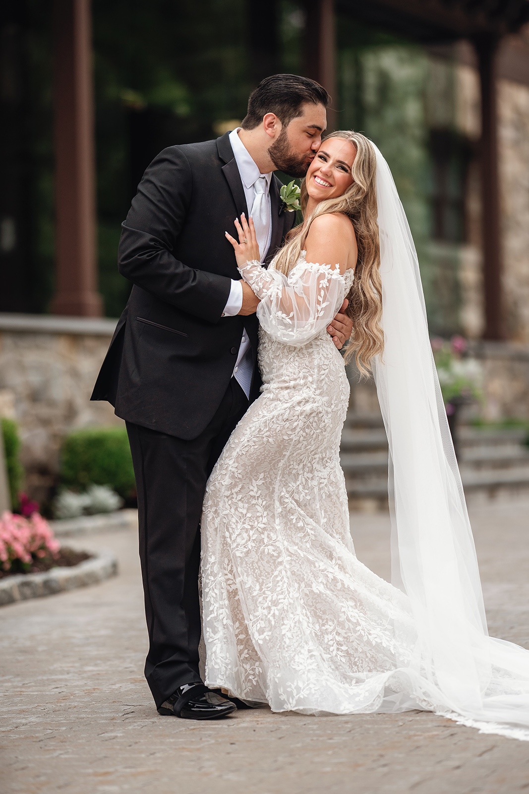 Groom in tux kissing bride in wedding dress