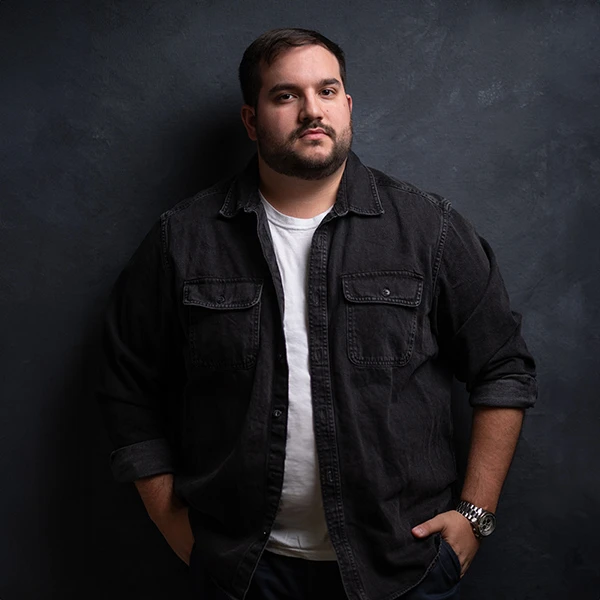 Rich, photographer posing in front of dark background wearing watch